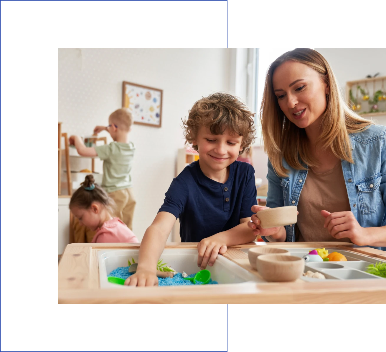 Smiling teacher assists child with sensory play