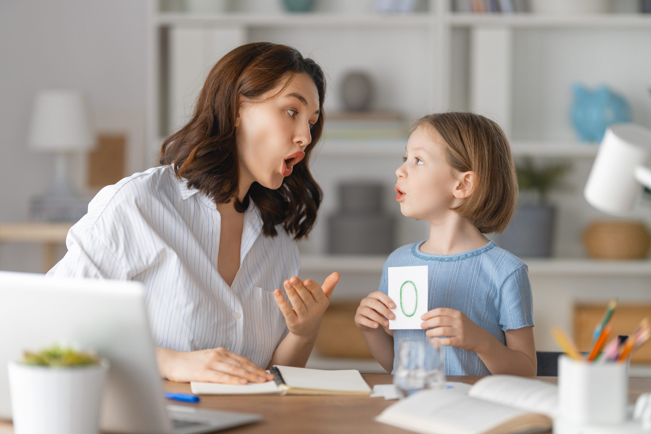 Mother teaching her daughter numbers using flashcards at home.