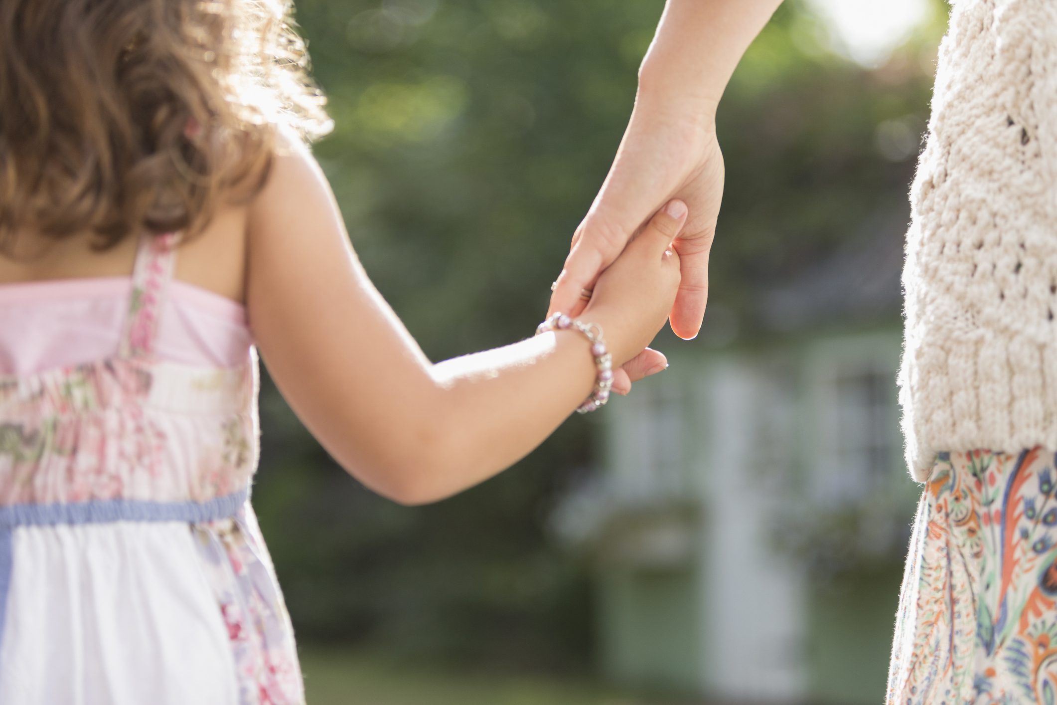 Close up rear view mother and daughter holding hands
